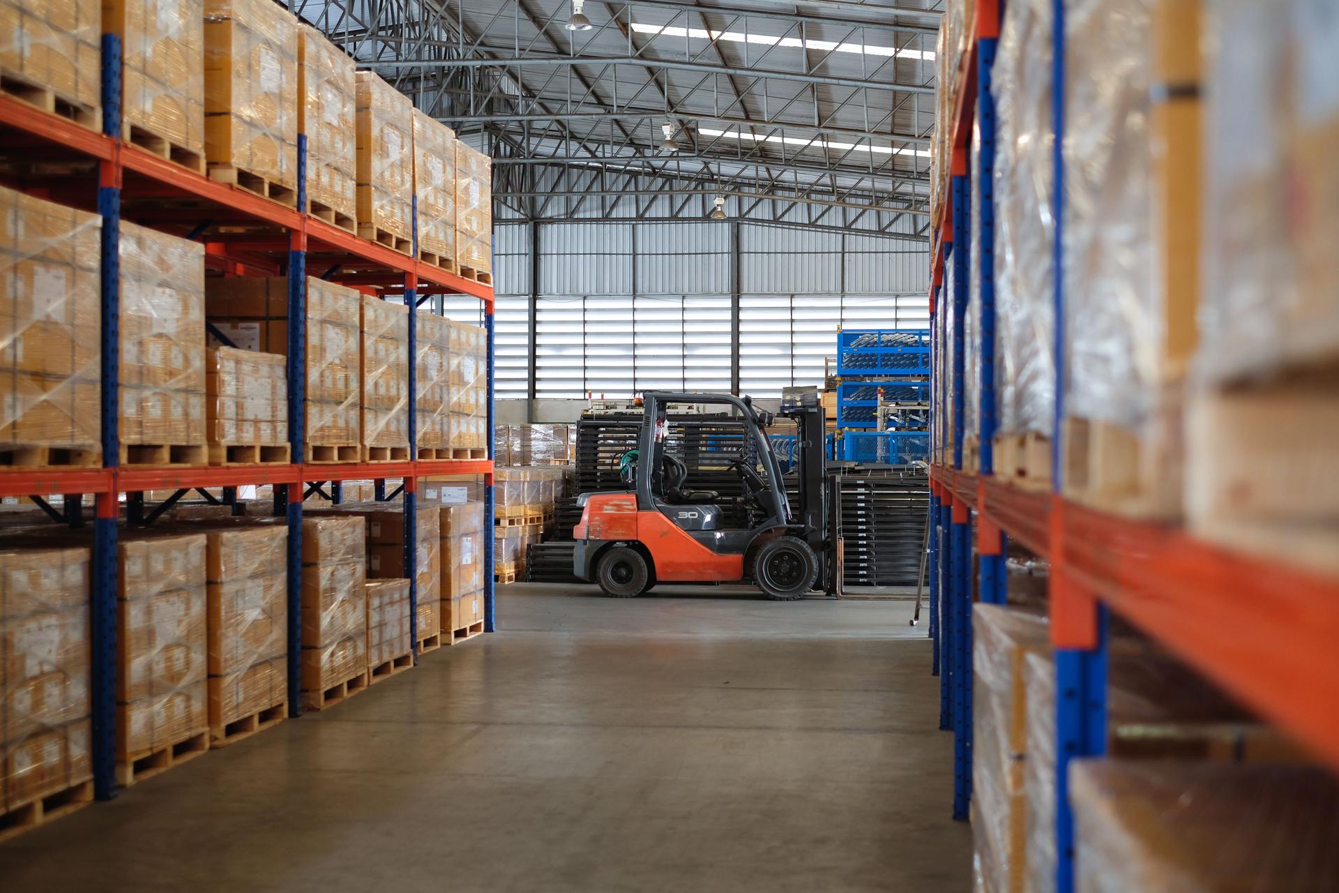 Modern warehouse of auto parts factory with forklift trucks parked near shelves.